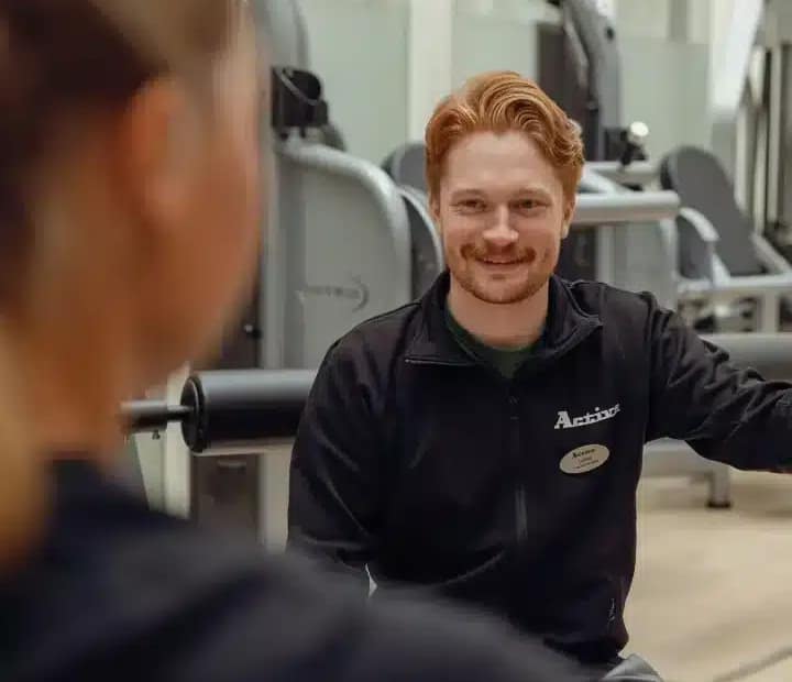 Active Rehab, Personlig tränare i samtal på rehabcenter, träningsutrustning i bakgrunden